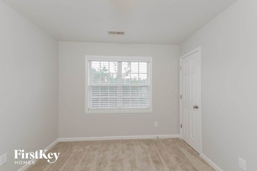 a bedroom with white walls and a window and a white door