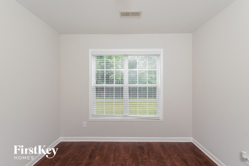 a bedroom with a large window and wood floors