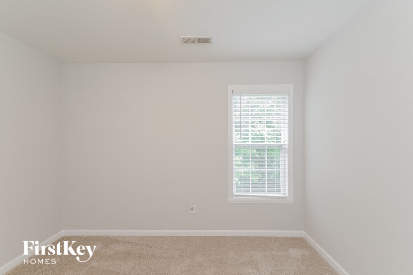 a bedroom with white walls and a window