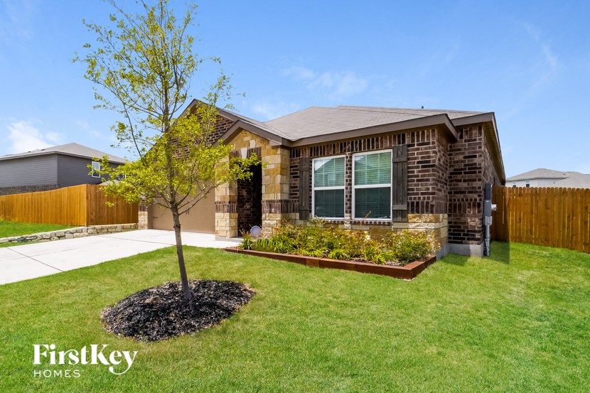 A house with a brown brick exterior and a small tree in the front yard.