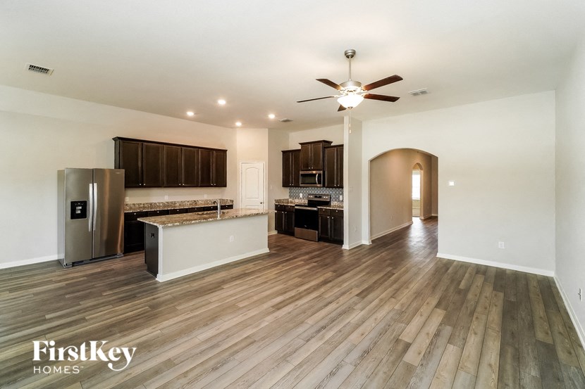 A spacious kitchen with wooden floors and a refrigerator.