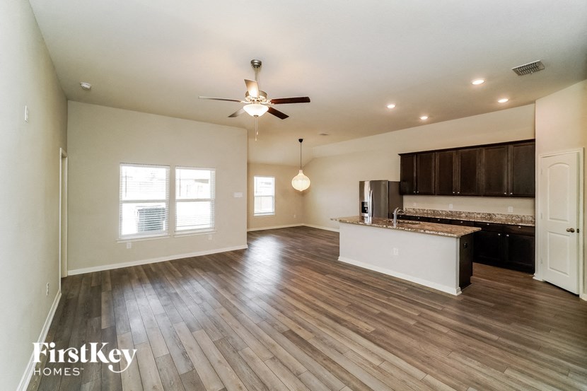 A spacious room with wooden floors and a ceiling fan.