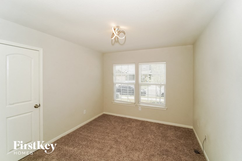A room with a carpeted floor and a window with blinds.