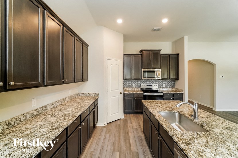 A kitchen with dark wood cabinets and granite countertops.