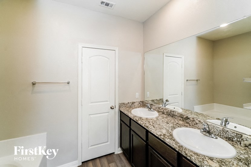 A bathroom with a white door and a counter with two sinks.