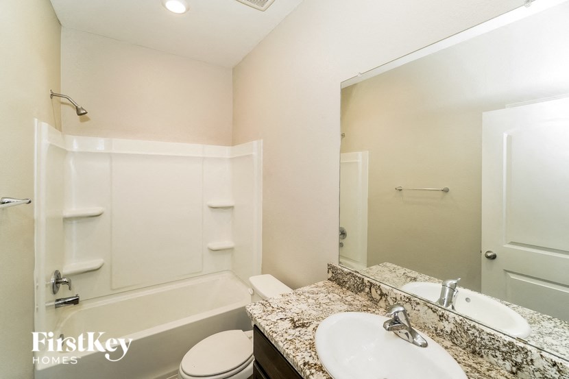 A bathroom with a marble countertop and a white sink.