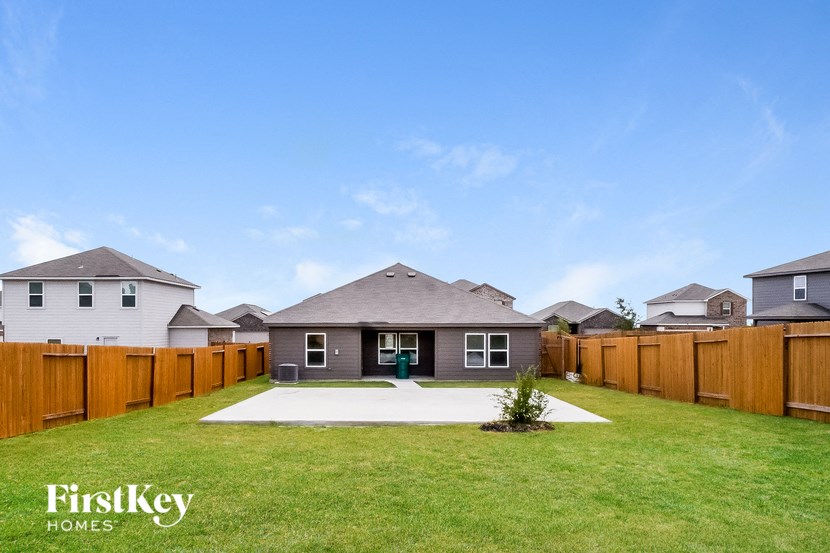 A house with a brown fence and a green plant in front.