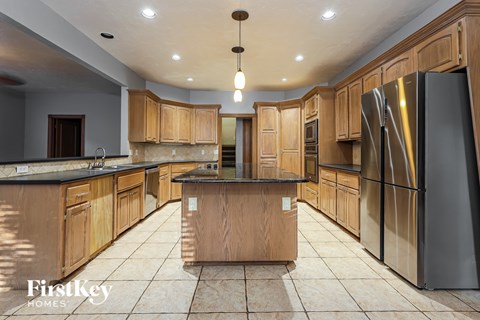 A kitchen with wooden cabinets and a large island in the middle.