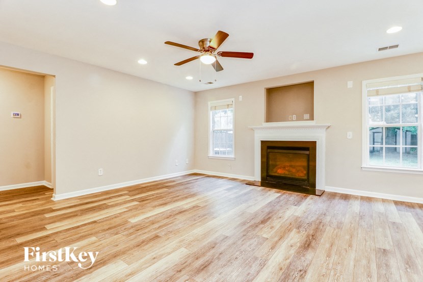 an empty living room with a fireplace and a ceiling fan