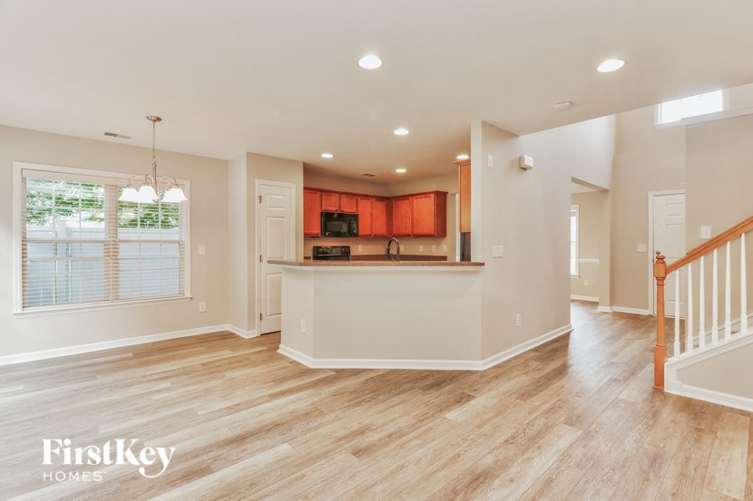 an empty living room with a kitchen and a staircase