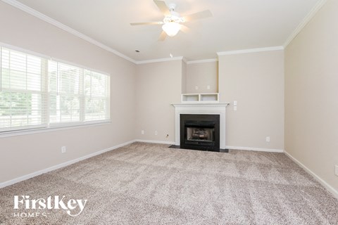 a empty living room with a fireplace and a ceiling fan