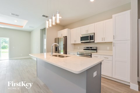A kitchen with a large island and a stainless steel microwave above it.