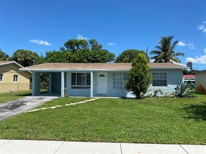 a blue house with a lawn and a palm tree