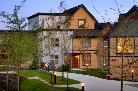A building with a white door and windows is lit up at dusk.