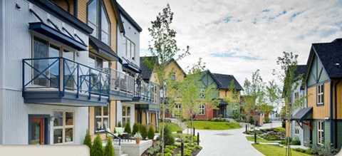 A row of modern houses with balconies and gardens.