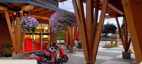 A red scooter is parked in front of a building with a red door.