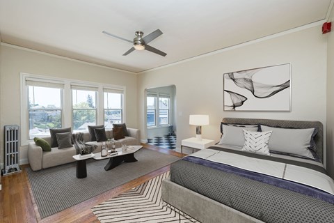 A bedroom with a large bed and a couch with a window view.