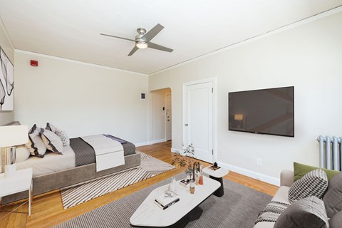 A living room with a grey couch, a white coffee table, and a ceiling fan.