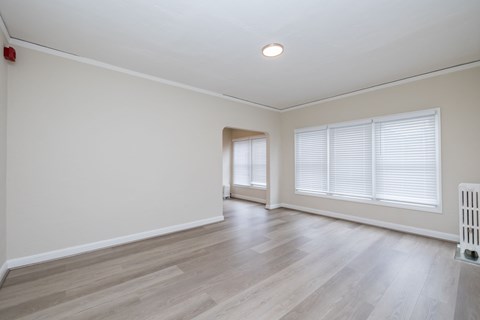 A room with wooden flooring and a window with blinds.