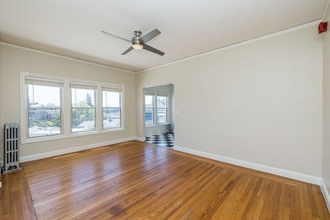 A room with a ceiling fan and wooden flooring.