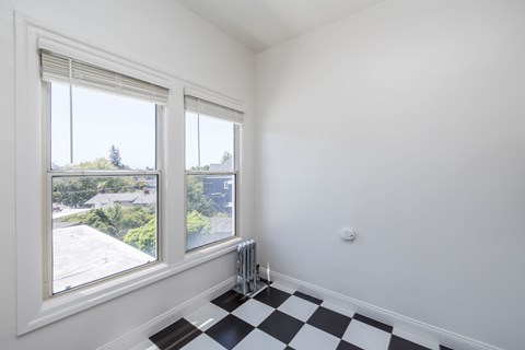 A room with a black and white checkered floor and a window overlooking a roof.