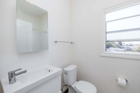 A white bathroom with a toilet, sink, and mirror.