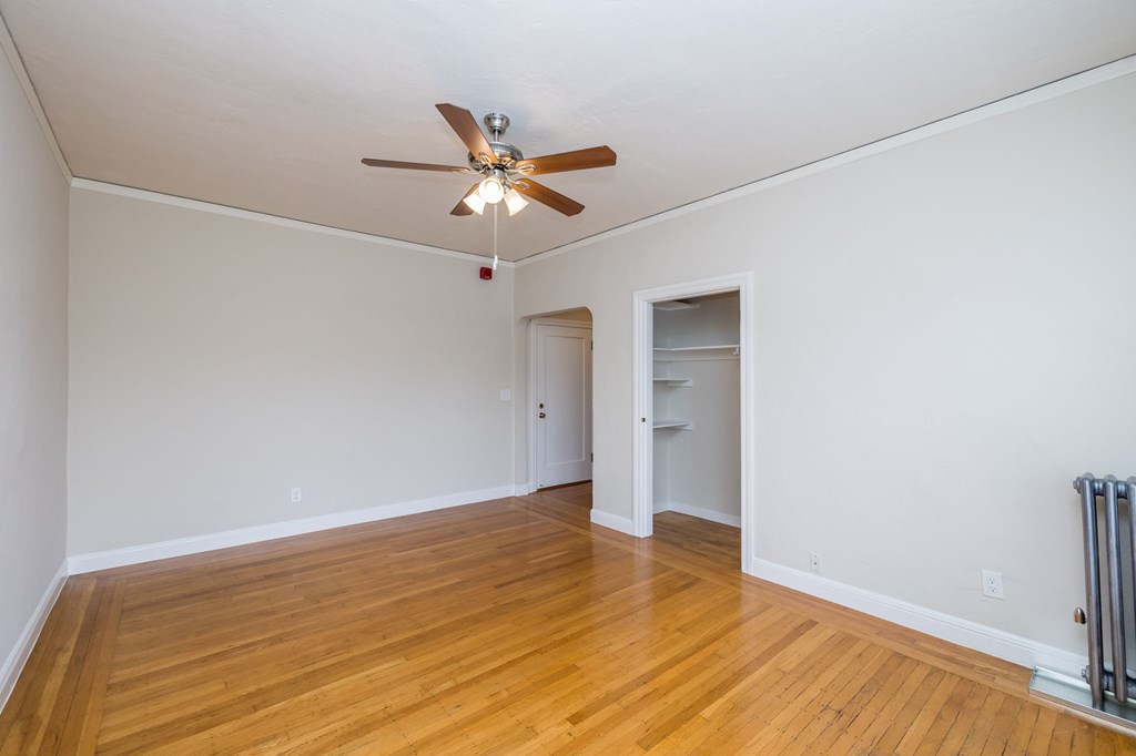 an empty living room with a ceiling fan and a closet