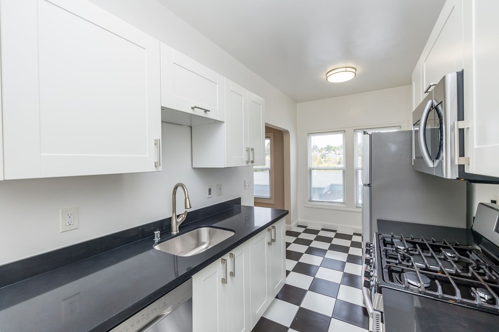 a kitchen with black and white checkered floor and white cabinets