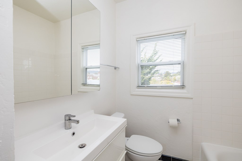 a white bathroom with a window and a sink and a toilet