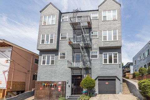 A grey two-story building with a fire escape on the side.