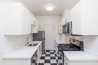 a kitchen with white cabinets and a black and white checkered floor