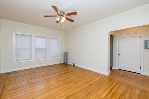 A room with a ceiling fan and wooden flooring.