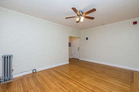 A room with a ceiling fan and wooden floors.