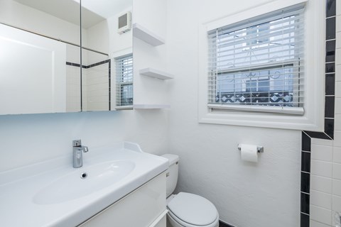 A white bathroom with a toilet, sink, and window.