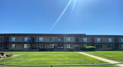 an apartment building with a green lawn and a blue sky