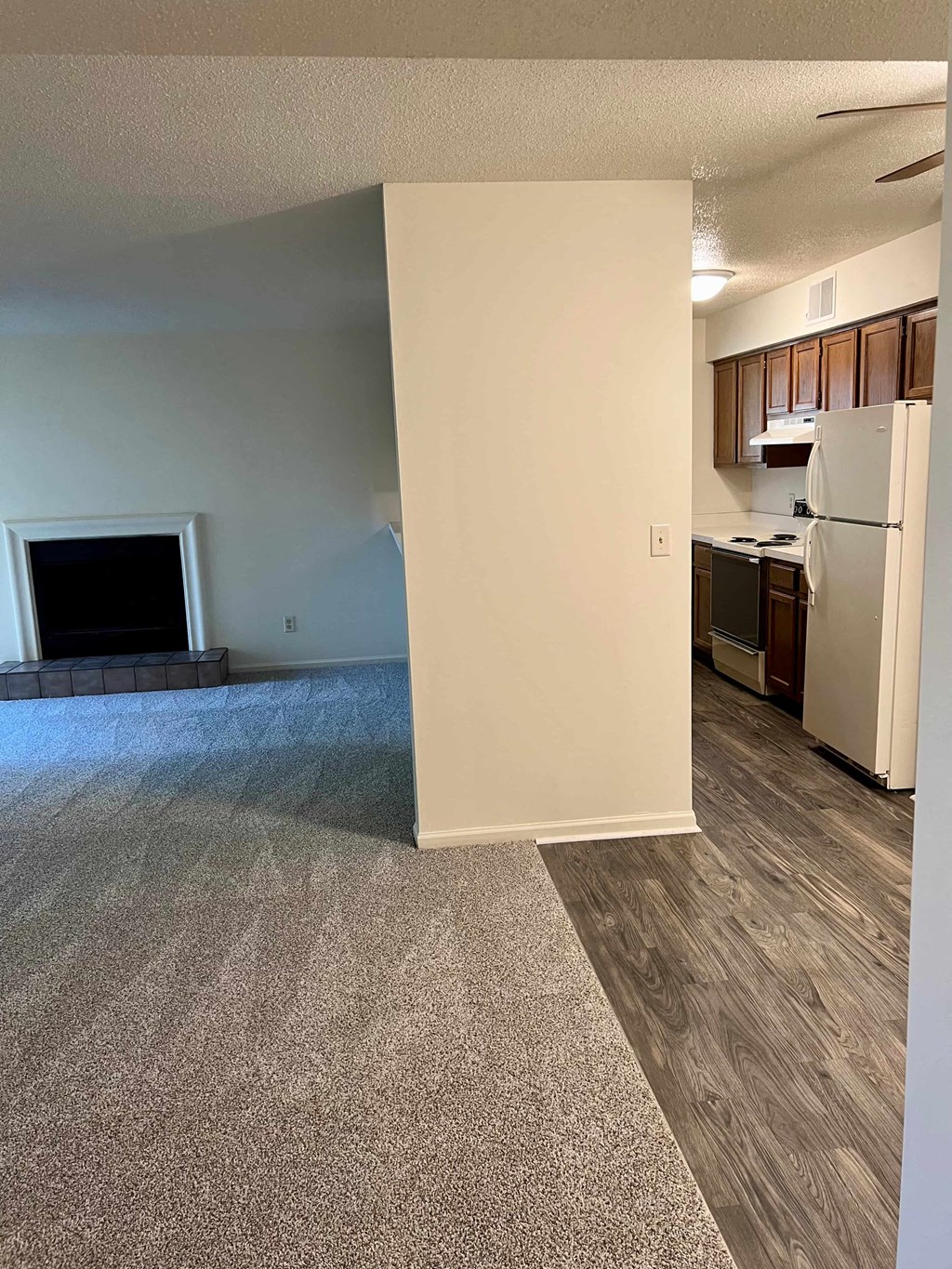 an empty living room with a fireplace and a kitchen