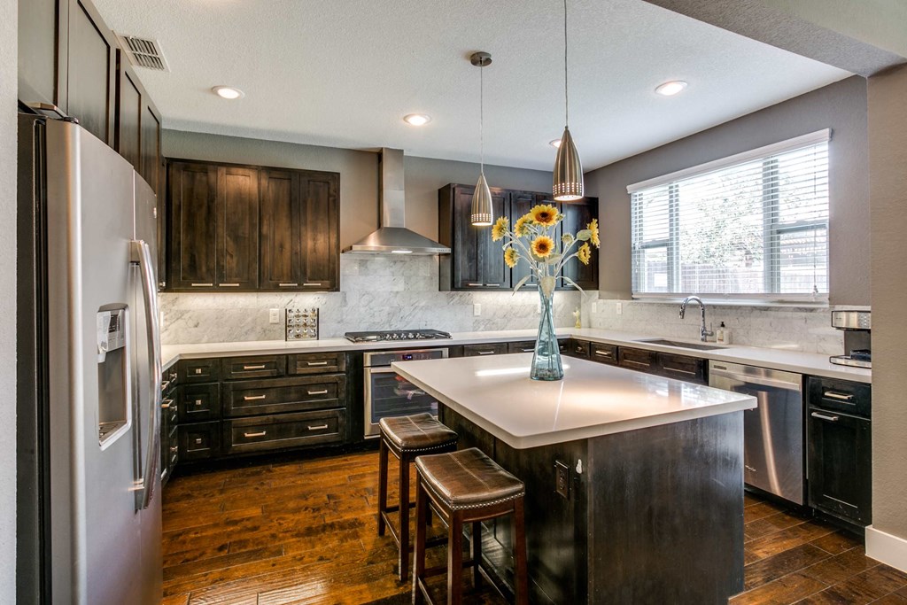 a kitchen with a center island and a stainless steel refrigerator