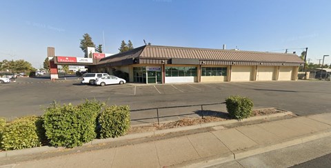 A parking lot with a building in the background and a car parked in the lot.