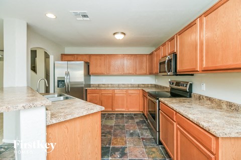 A kitchen with wooden cabinets and a granite counter top.