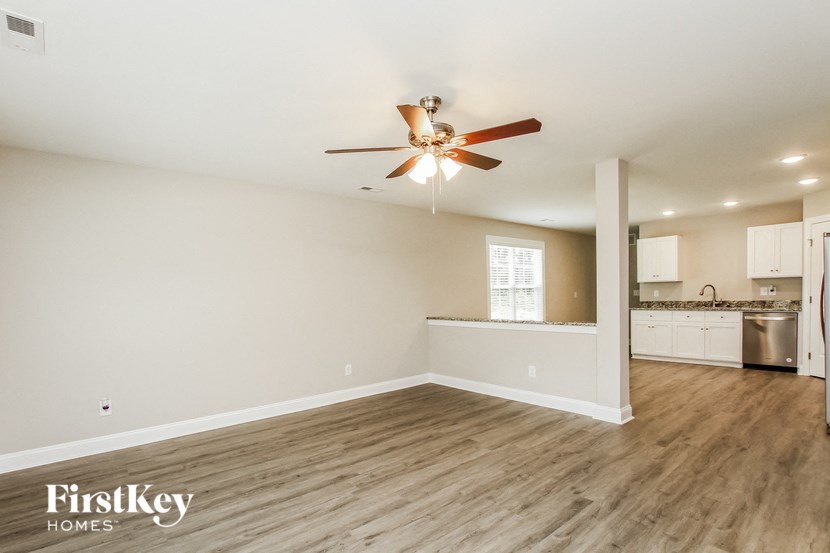 A spacious room with a fan and wooden flooring.
