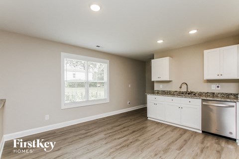 A kitchen with a stainless steel dishwasher and white cabinets.