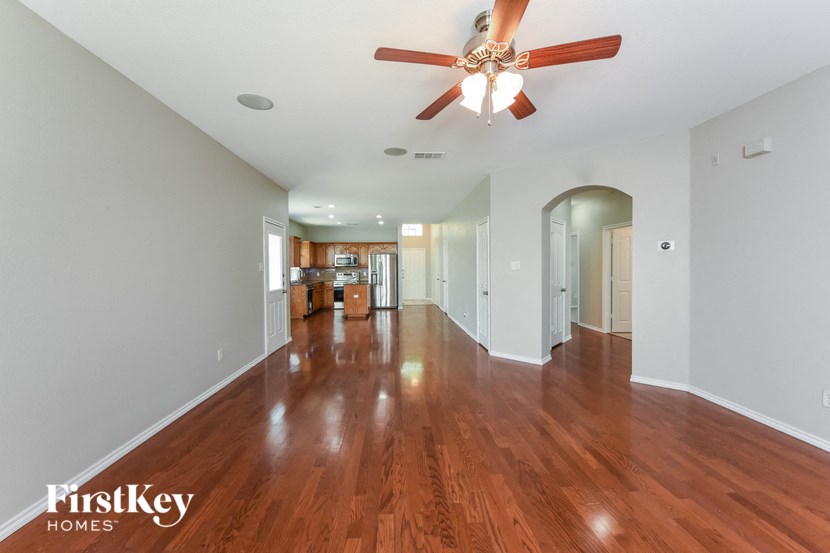 A spacious room with wooden floors and a ceiling fan.