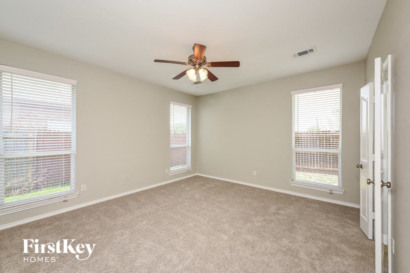 A room with a ceiling fan and two windows.