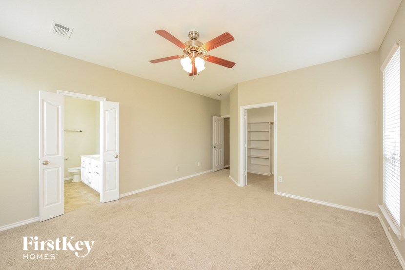 A room with a ceiling fan and two open doors.