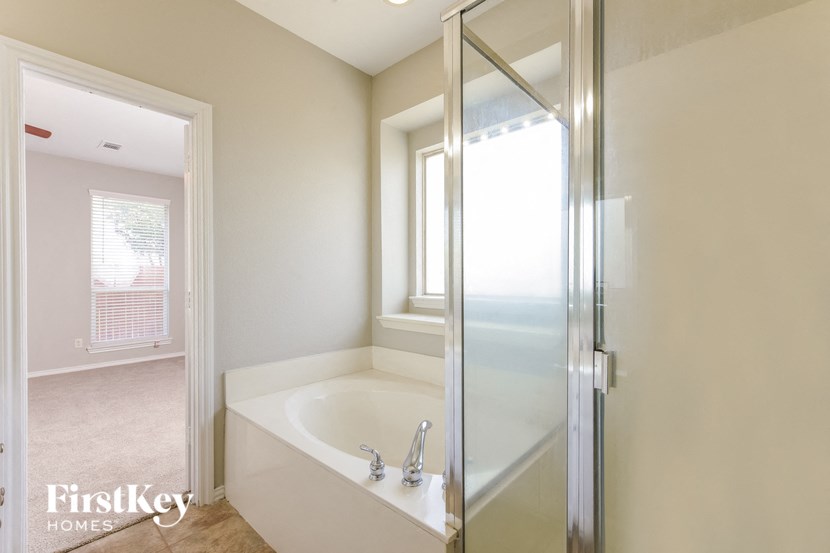 A white bathroom with a glass shower door and a bathtub.