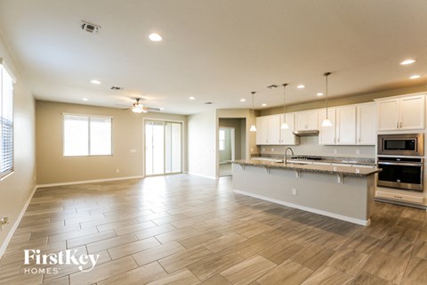 A spacious kitchen and living room with wooden flooring and white walls.