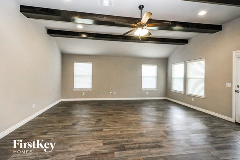 an empty living room with wood floors and a ceiling fan