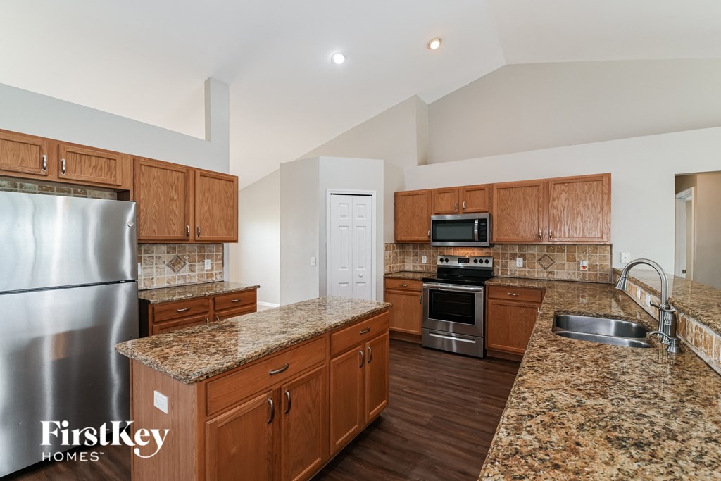 A kitchen with granite countertops and wooden cabinets.