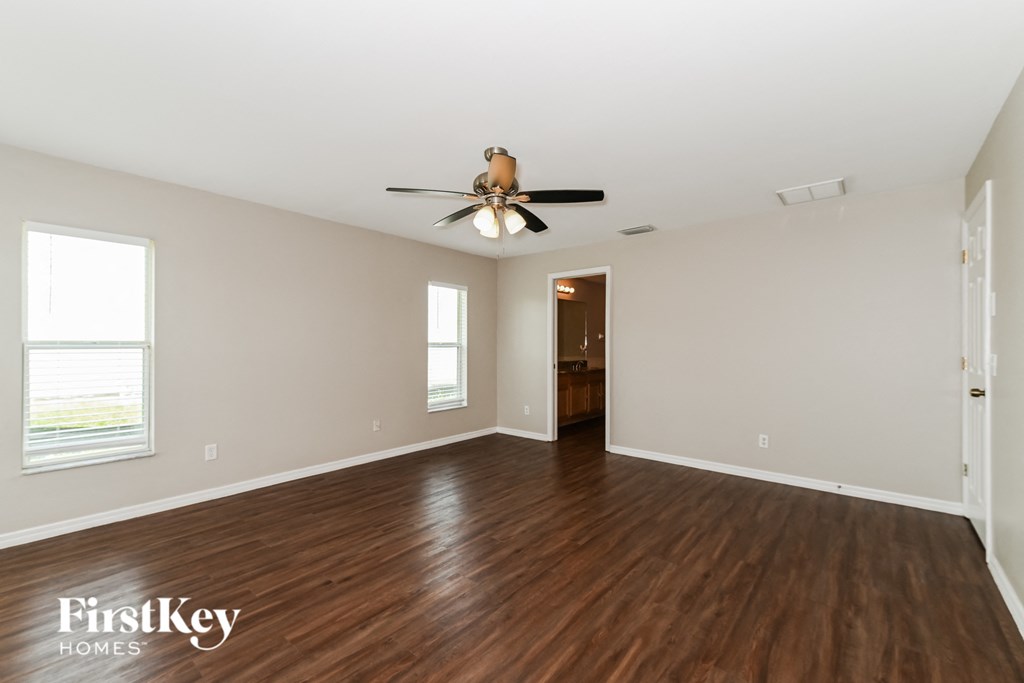 A spacious room with wood flooring and a ceiling fan.