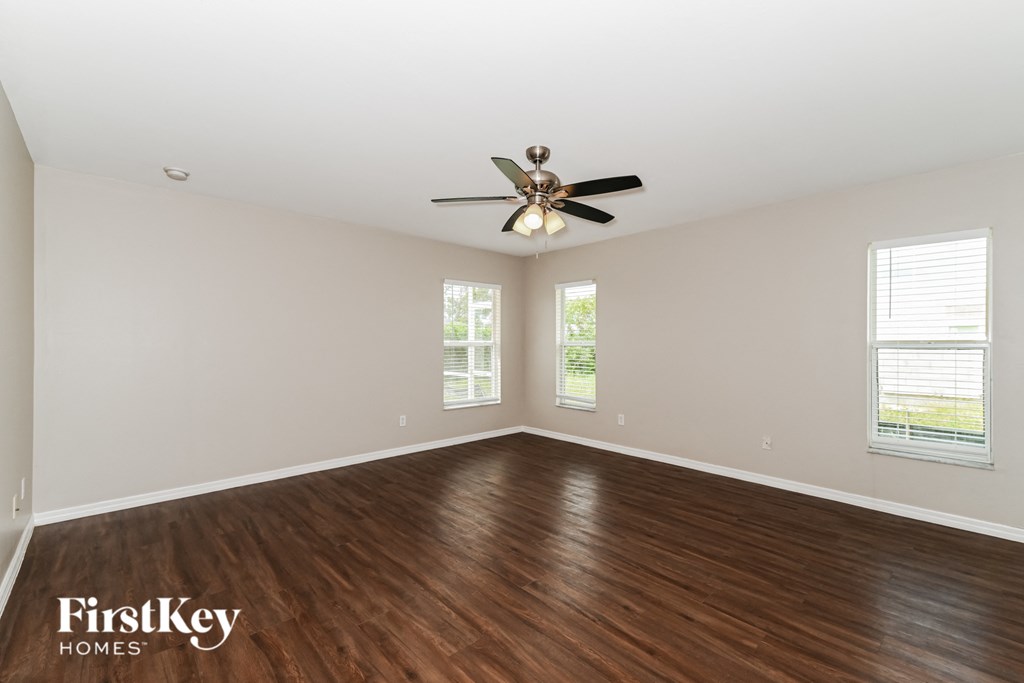 A spacious room with a ceiling fan and wooden flooring.